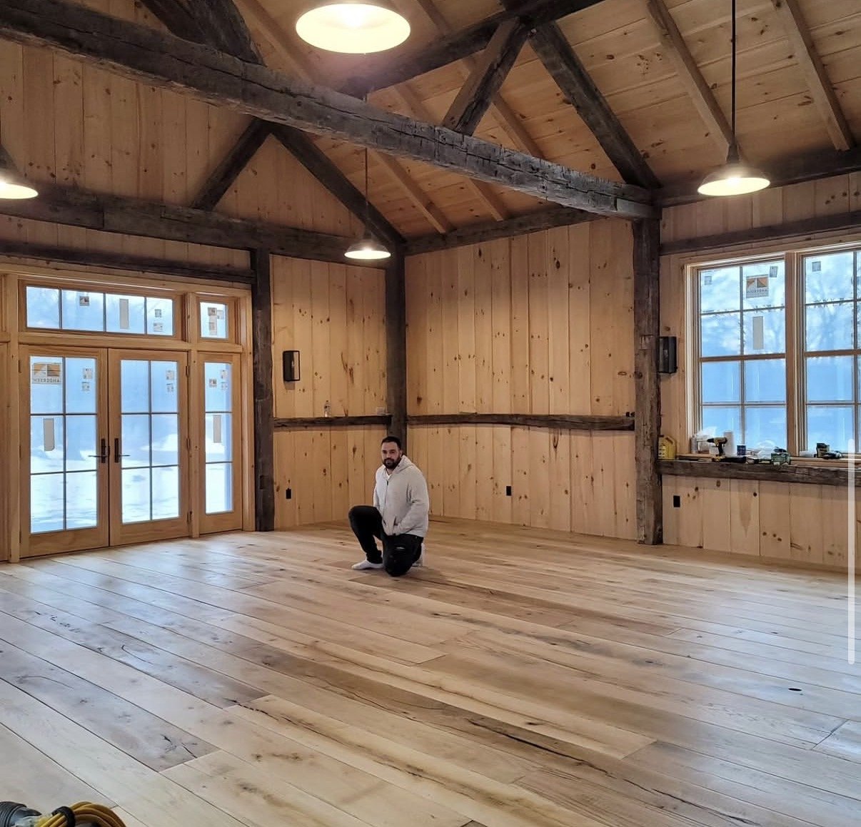 Andre Ferreira kneeling on a finished barn floor he installed