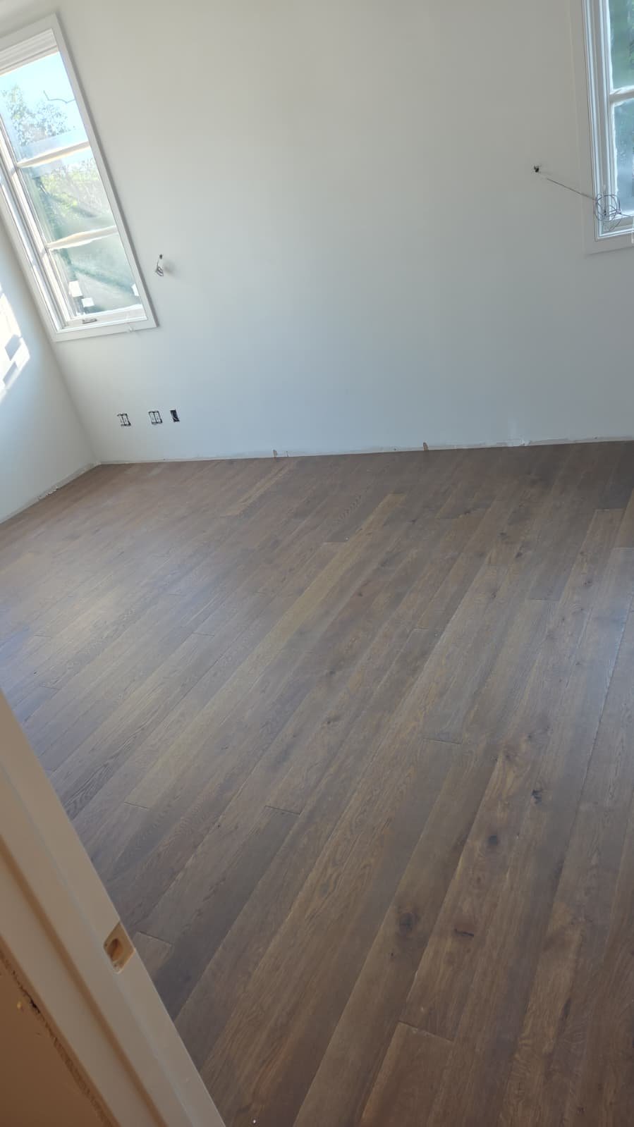 Finished wide plank engineered oak floor in a bright bedroom